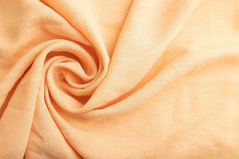 Fragment of orange linen tissue. Top view, flat lay, natural textile background and texture. wave concept, abstract, spiral form