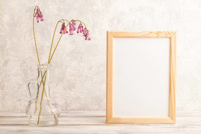 Wooden frame with pink dicentra, broken heart in glass on gray concrete background. side view, copy space, mockup, template, spring, summer minimalism concept