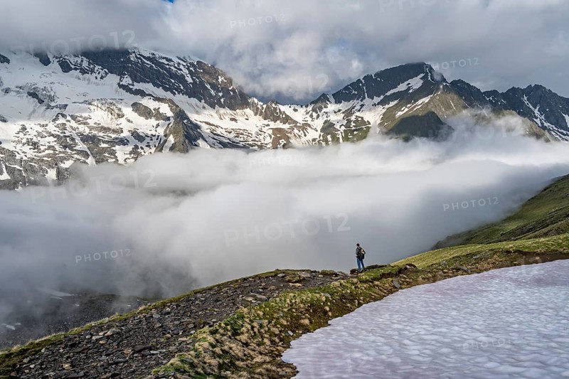 Mountaineer in front of mountain landscape with high fog in the valley, summit Hochfeiler and Hochsteller with clouds, glacier Schlegeiskees, Berliner Höhenweg, Zillertal Alps, Tyrol, Austria, Europe