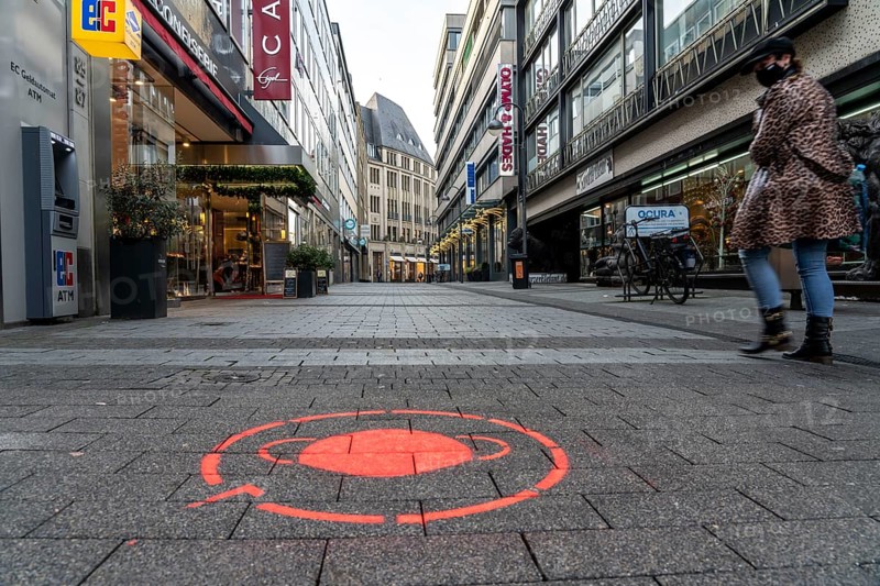First day of the Christmas lockdown in the Corona crisis, empty shopping street, closed shops, hardly any passers-by, logo on the floor, notice about the obligation to wear masks, Brückenstraße, in Cologne, North Rhine-Westphalia, Germany, Europe