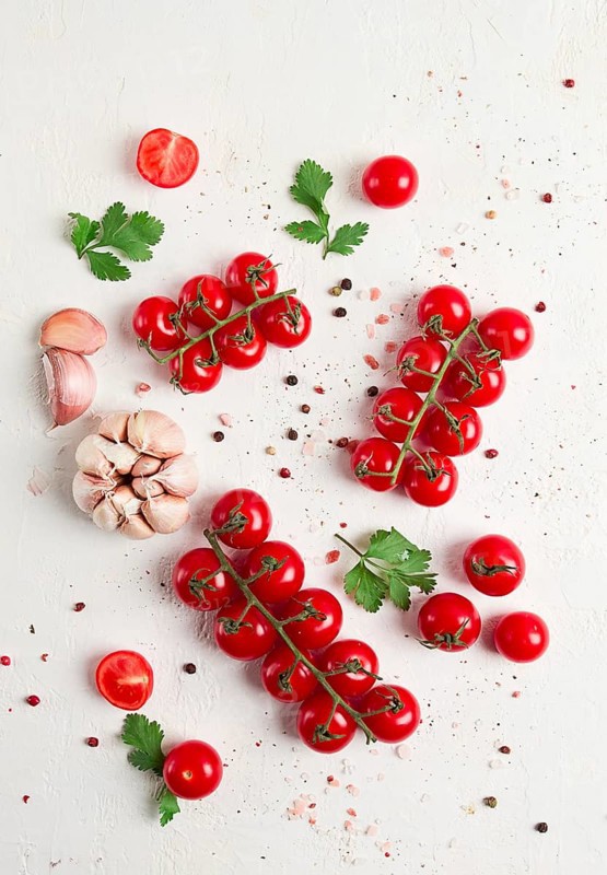 Branch with mini cherry tomatoes, with spices and herbs, garlic, food background, top view, on a white background