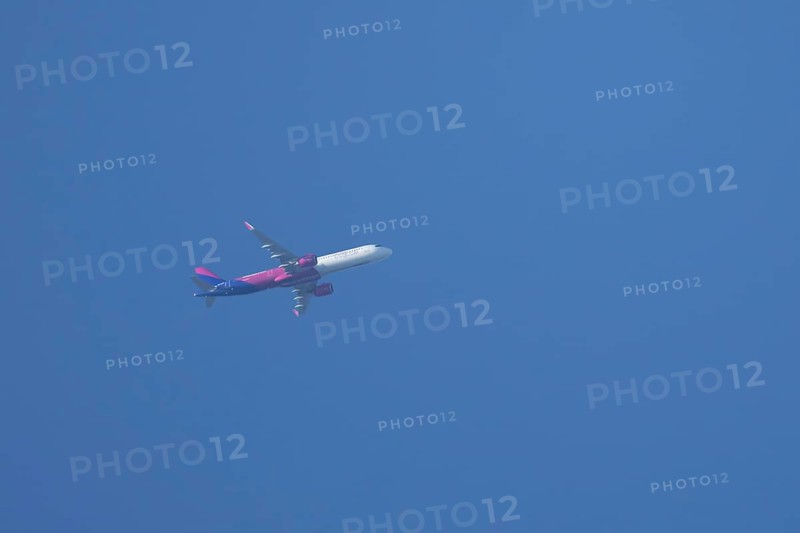 Airbus A320 aircraft of Wizz air airlines in flight across a blue sky, England, United Kingdom, Europe