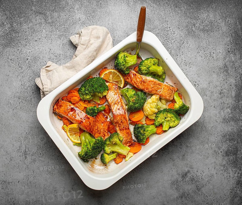 Top view of healthy baked fish salmon steaks, broccoli, cauliflower, carrot in casserole dish. Cooking a delicious low carb dinner, healthy nutrition concept, food photography
