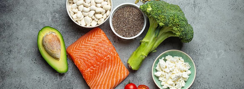 Selection of healthy food products if a person have diabetes: salmon fish, broccoli, avocado, beans, vegetables, seeds on grey background from above. Healthy diabetes diet, food photography
