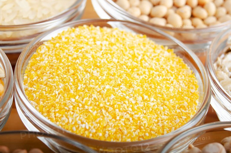 Corn grits closeup in glass bowl on wooden kitchen table, non-perishable, long shelf life food concept