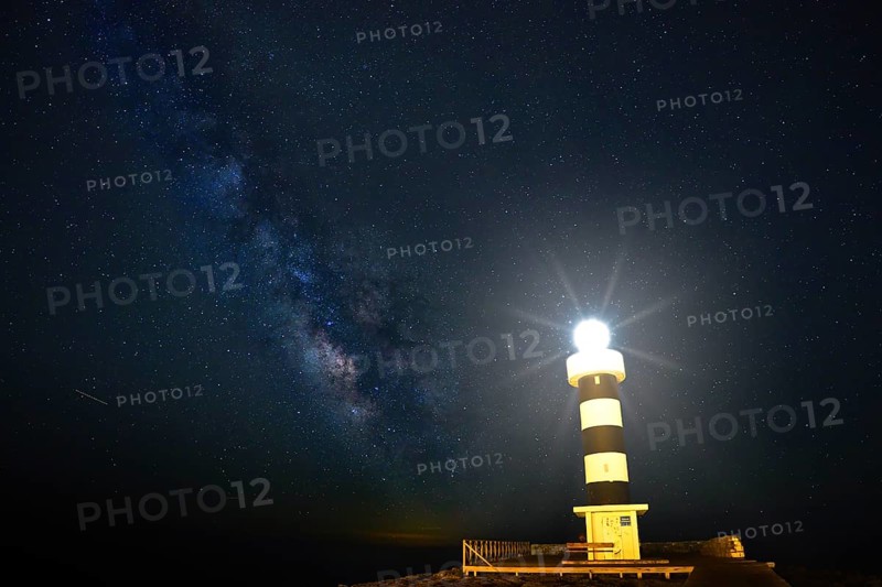 Lighthouse illuminated under a twinkling starry sky with the Milky Way in the background, Colonia St Jordi, Majorca Spain