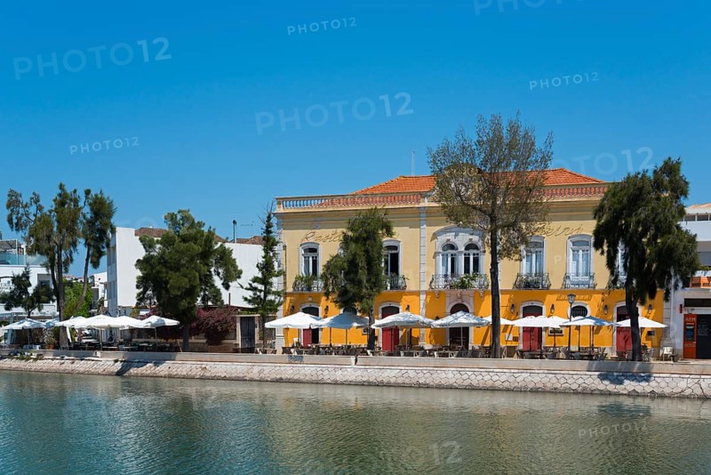Yellow building with terrace area by the river, surrounded by trees and a restaurant in the Algarve, Gilão River, GilaoTavira, Faro, Algarve, Portugal, Europe