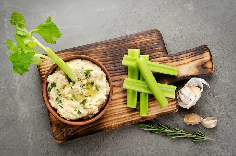 Flat lay view at vegetable Hummus dip dish topped with chickpeas and olive oil served with celery slices