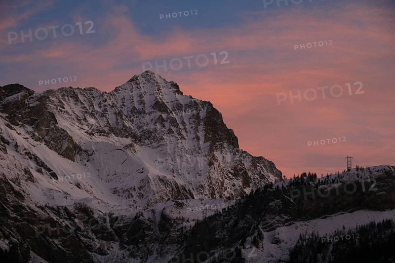 Sunlit pink clouds over Mount Arpelistock in winter