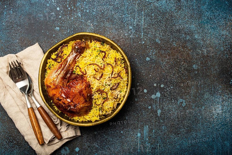 Delicious Indian dish Biryani chicken with basmati rice in metal brass old bowl on table rustic stone background. Traditional non-vegetarian food of India, top view with space for text, food photography