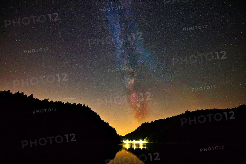 The Milky Way shines in the night sky above a quiet lake surrounded by dark trees, Alp Stausee, Sankt Blasien, Black Forest, Baden- Württemberg, Germany, Europe