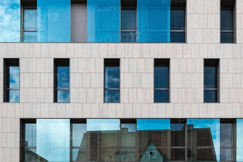 Ingolstadt, Bavaria, Germany, 07 27 2018: Rectangular facade with glass and cocnrete of an office building, reflecting a city roof, Europe