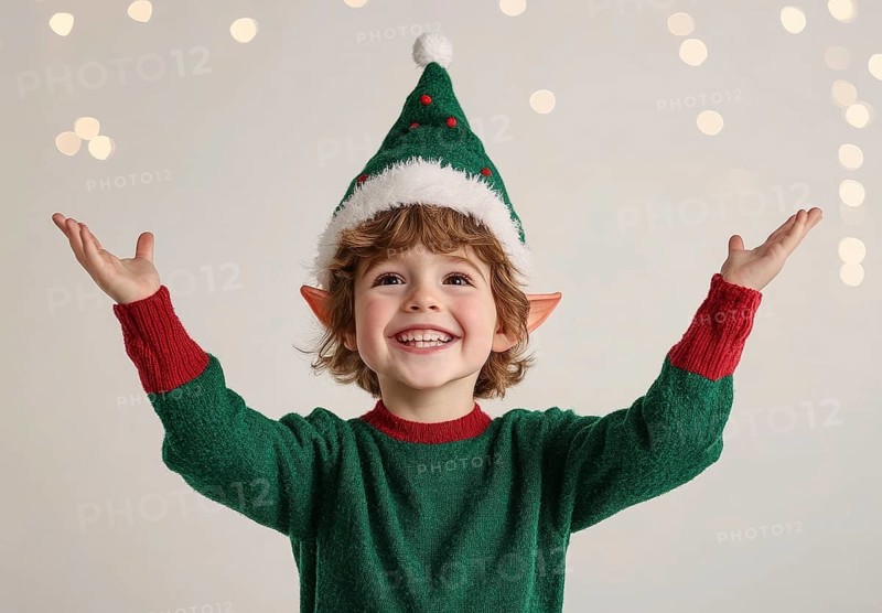 A cheerful boy dressed as a festive elf with green sweater and red details, with Christmas hat and elf ears, smiling with his arms up in a playful and cheerful pose. on a transparent background, AI generated