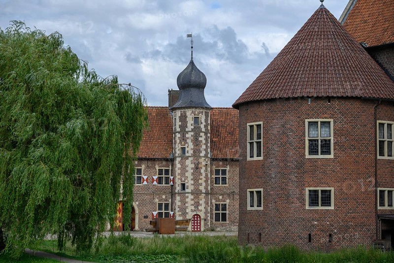 Historic castle with striking towers, red tiled roofs and a moat, surrounded by trees, Raesfeld, North Rhine-Westphalia, Germany, Europe