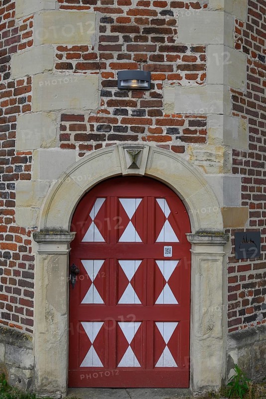 Historic red wooden door with white triangular patterns in a stone wall with bricks, Raesfeld, North Rhine-Westphalia, Germany, Europe