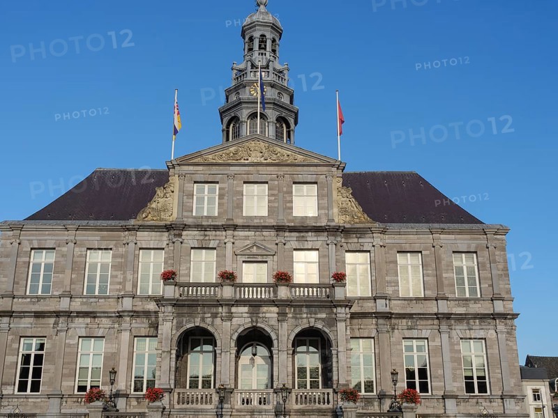 A historic building with a stone façade and several windows standing against the blue sky, maastricht. netherlands