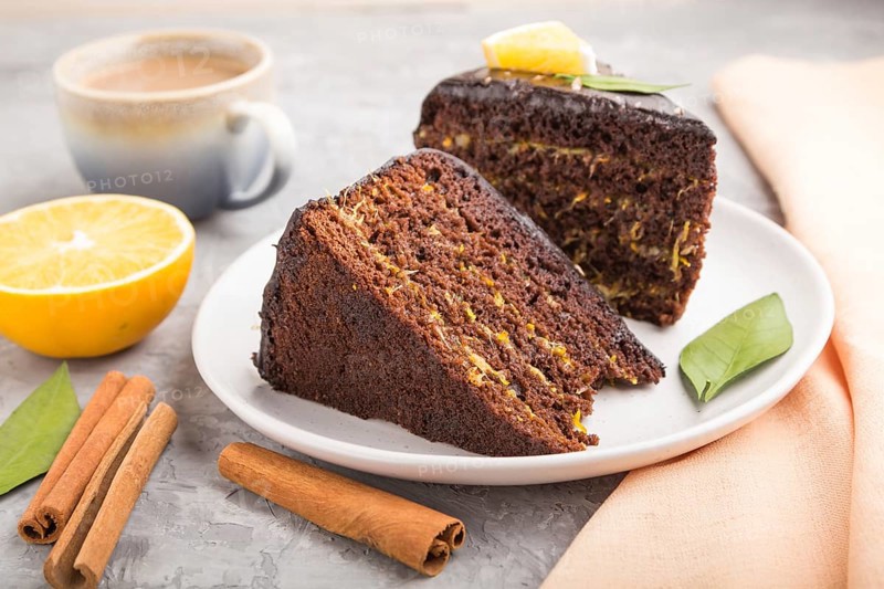 Homemade chocolate cake with orange and cinnamon with cup of coffee on a gray concrete background with orange textile. side view, close up, selective focus