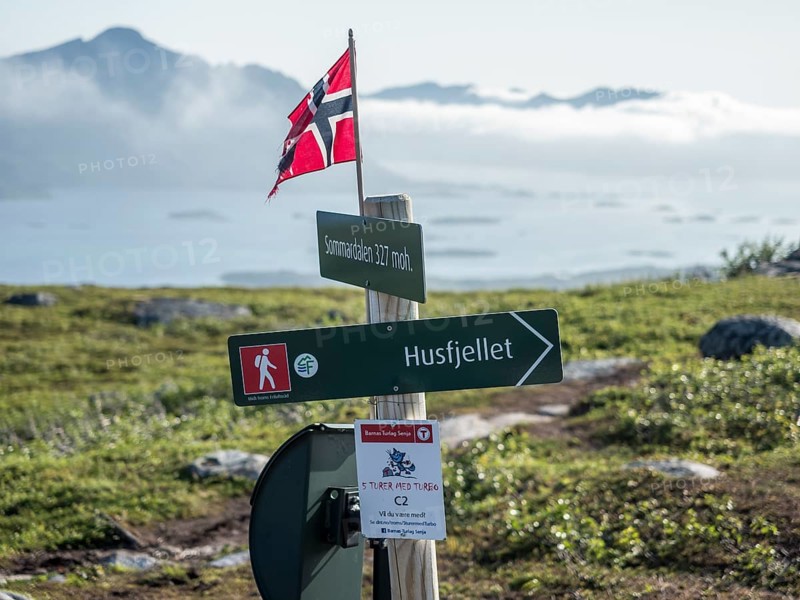 Signpost on the way up to Husfjellet, clouds cover mountains and fjord Bergsfjorden, Senja island, Norway, Europe