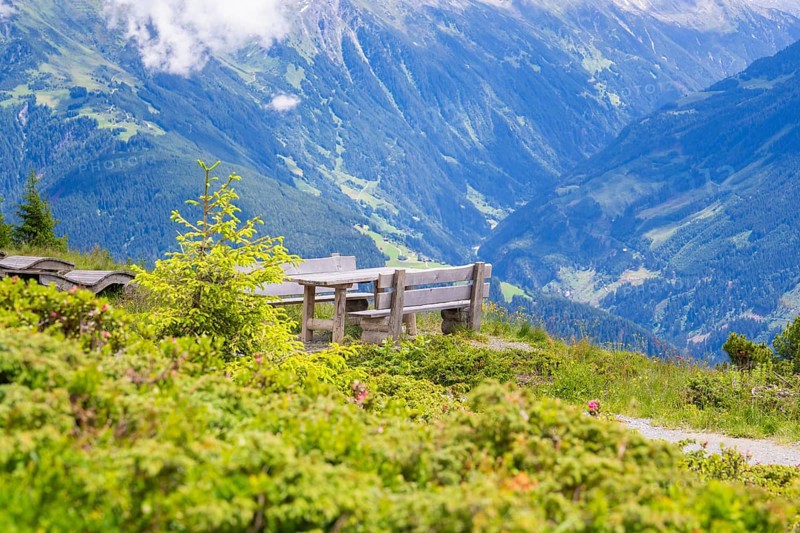 A bench on a hill with a view of the impressive mountain landscape under a partly cloudy sky, Penken, Zillertal, Austria, Europe
