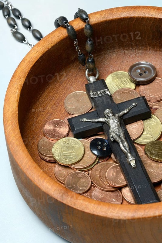 Crucifix with coins and buttons in a wooden bowl, church and money
