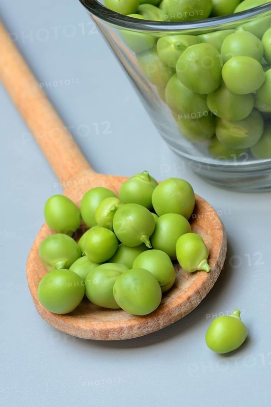 Fresh green peas in wooden spoon, Pisum sativum