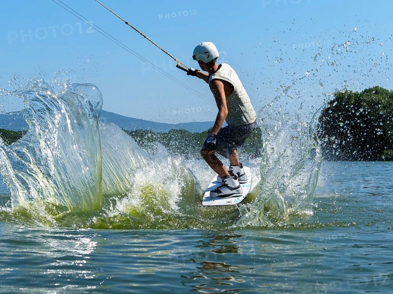 Young man jumping with wakeboard into the lake, water sports, water skiing in wakepark, Stráž pod Ralskem, Czech Republic, Europe