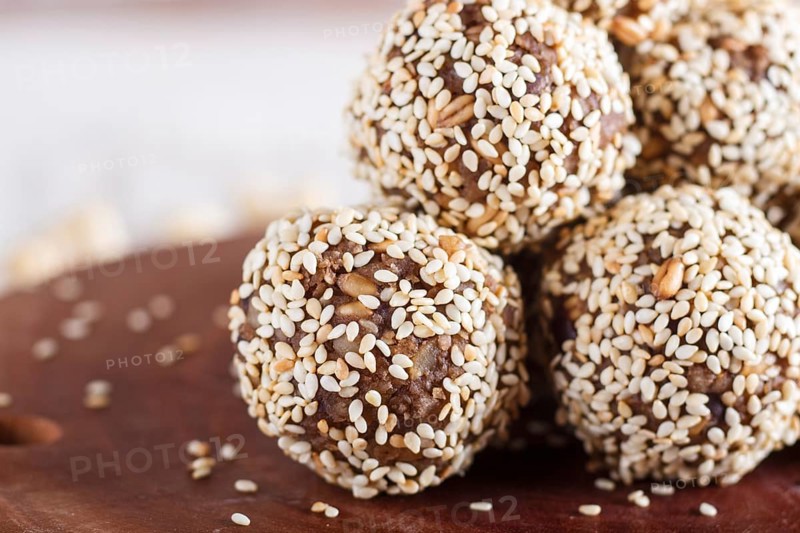 Energy balls cakes with almonds, sesame, cashew, walnuts, dates and germinated wheat on wooden board, side view, close up