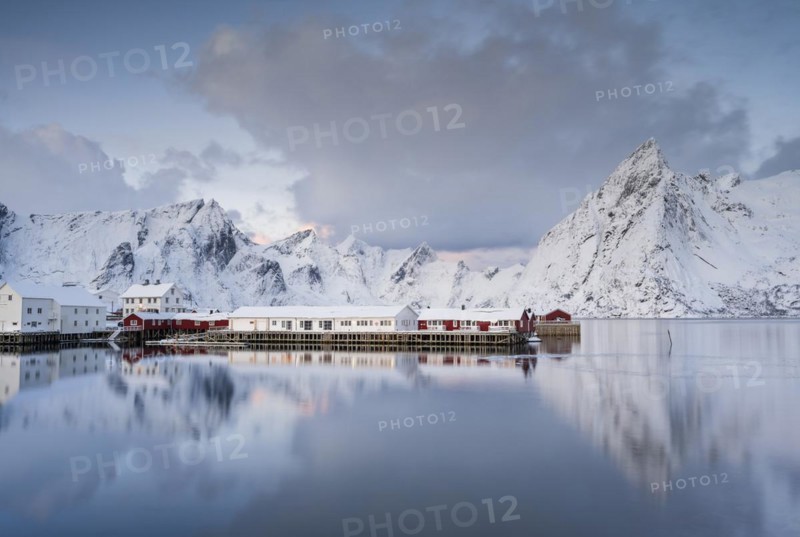 Rorbuer huts of Hamnoy at the fjord, snowy mountains in the background, Hamnøy, Reine, Moskenesøya, Lofoten, Norway, Europe