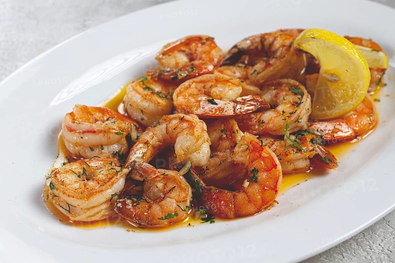 Fried tiger prawns, jumbo, in garlic sauce, in butter, with herbs, on a white plate, homemade, no people