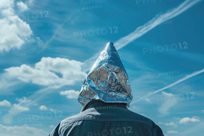 Chemtrail conspiracy theory concept with back view of man with tinfoil hat looking at sky with condensation trails. Generative Ai, AI generated