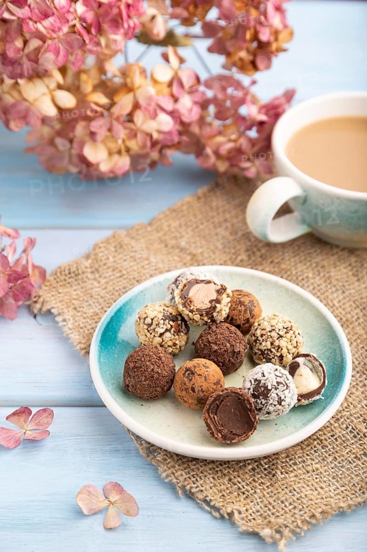 Chocolate truffle candies with cup of coffee on a blue wooden background and linen textile. side view, close up, selective focus