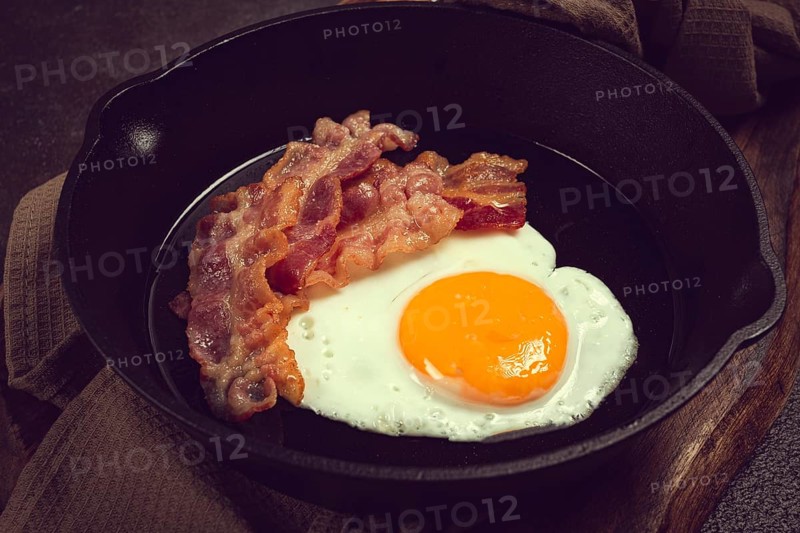 Fried egg with bacon, in a cast-iron pan, breakfast, top view, close-up, homemade, no people
