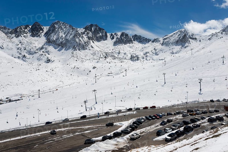 Schneebedecktes Skigebiet in den Bergen mit Skiliften und Autos auf dem Parkplatz unter einem klaren blauen Himmel, Skigebiet, El Pas de la Casa, Pyrénées-Orientales, Encamp, Fürstentum Andorra, Pyrenäen