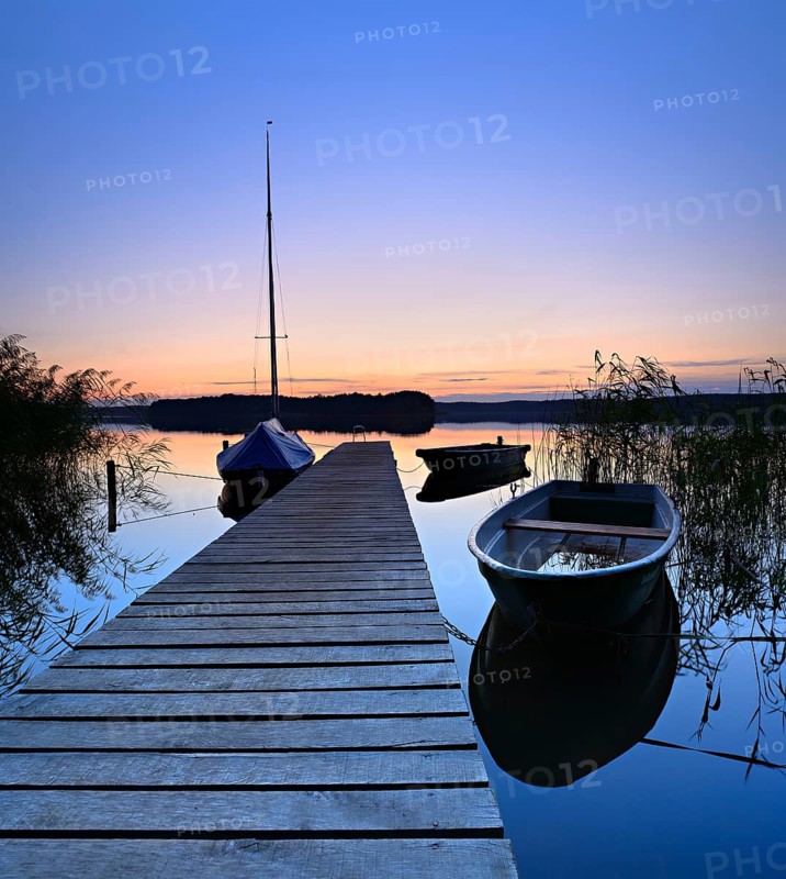 Quiet lake with jetty and boats after sunset at dusk, Großer Lychensee, Lychen, Brandenburg, Germany, Europe