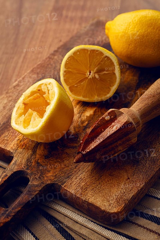 Lemons and a wooden manual citrus juicer, on a chopping board, close-up, no people