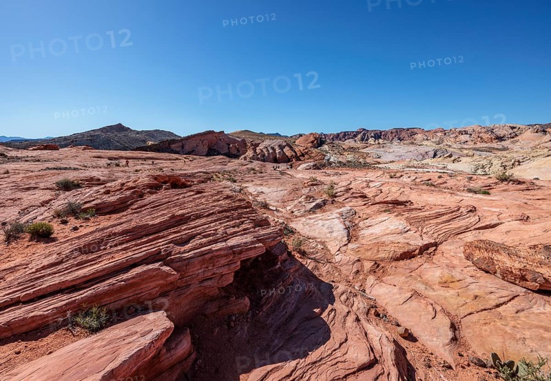 Hikers in the distance along the layered sandstone Fire Wave Trail at Valley of Fire State Park near Overton, Nevada