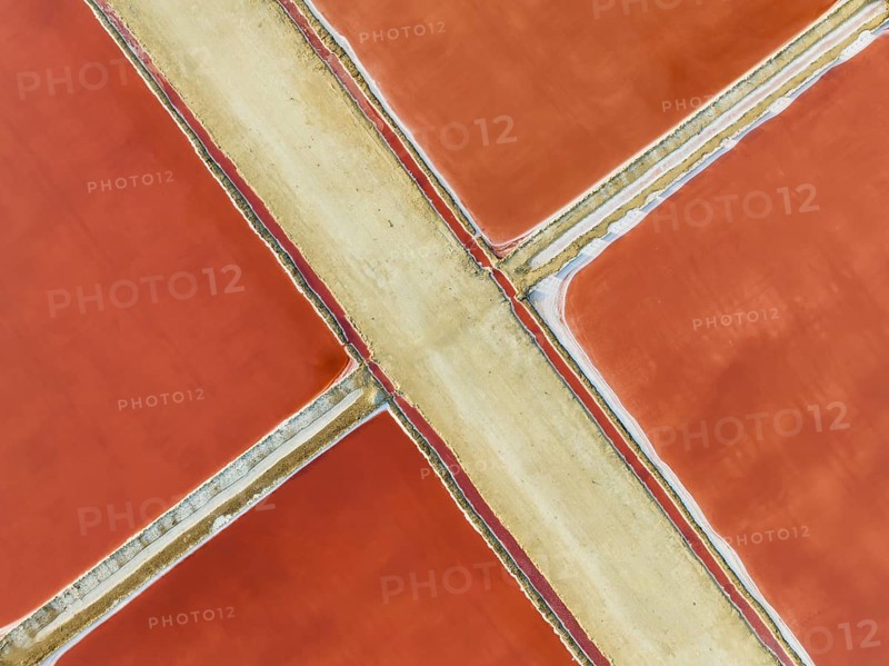 Saline ponds at the Bonanza salt works near Sanlúcar de Barrameda. The red colour depends on the level of salinity and is directly caused by the algae Dunaliella salina and brine shrimp. Aerial view. Drone shot. Cádiz province, Andalusia, Spain, Europe