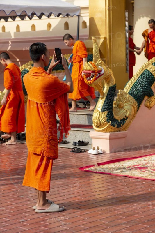 Monk in front of a Buddha statue, Bhumispara-mudra, Buddha Gautama at the moment of enlightenment, Wat Ong Teu, Vientiane, Laos, Asia