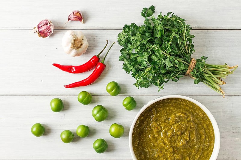 Tkemali sauce, traditional Georgian cuisine, green cherry plum, with ingredients for sauce, cilantro, mint, hot pepper, garlic, on a white wooden table, close-up, rustic, food background, no people, selective focus, sauce, green sauce, tkemali, georgian cuisine, homemade