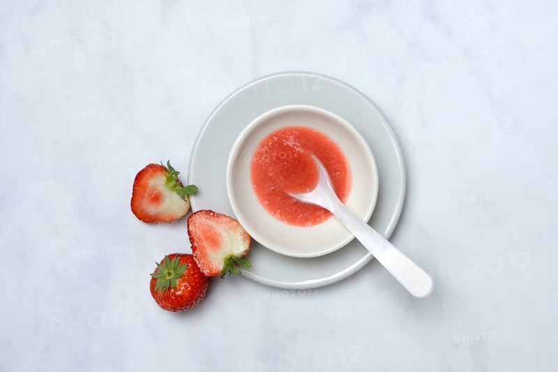 Strawberry sauce in small bowls and strawberries, strawberry coulis