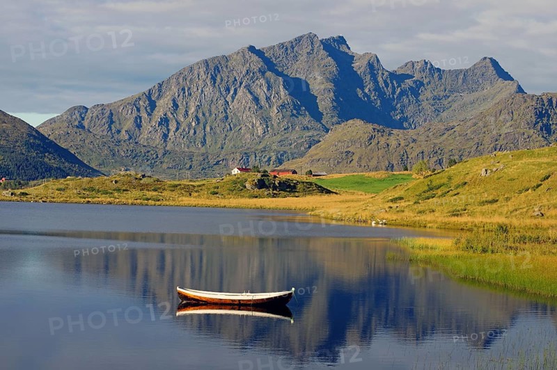 A small wooden boat floats on a calm lake with majestic mountains in the background, Leknes, Vestvågøya, Lofoten, Nordland, Norway, Europe
