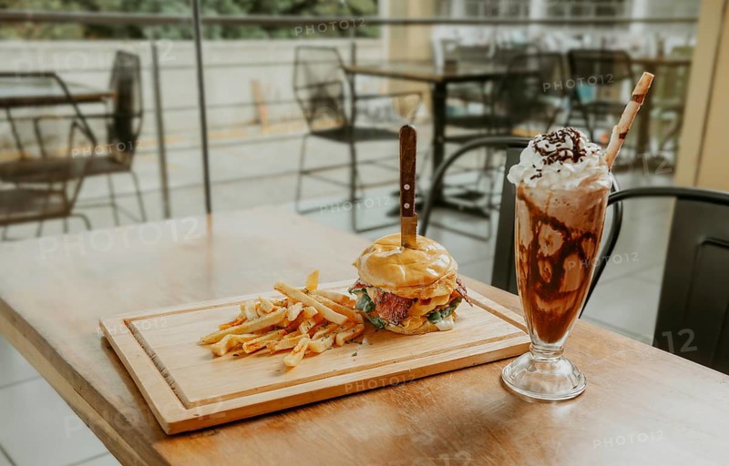 Big hamburger with fries and milkshake on restaurant table. Classic burger with fries and milkshake on wooden board with copy space