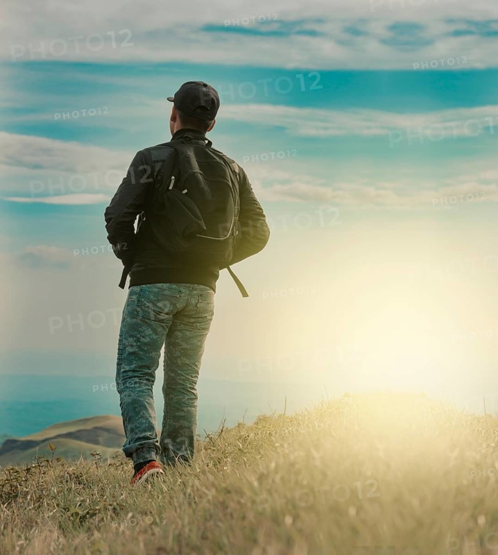 Rear view of backpacker man walking in the mountain. Low angle of backpacker man walking in the countryside