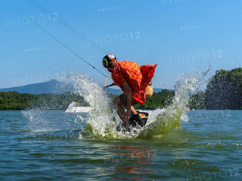 Young casual man with flapping shirt on wakeboard jumping into the lake, water ski and wakepark, Stráž pod Ralskem, Czech Republic, Europe