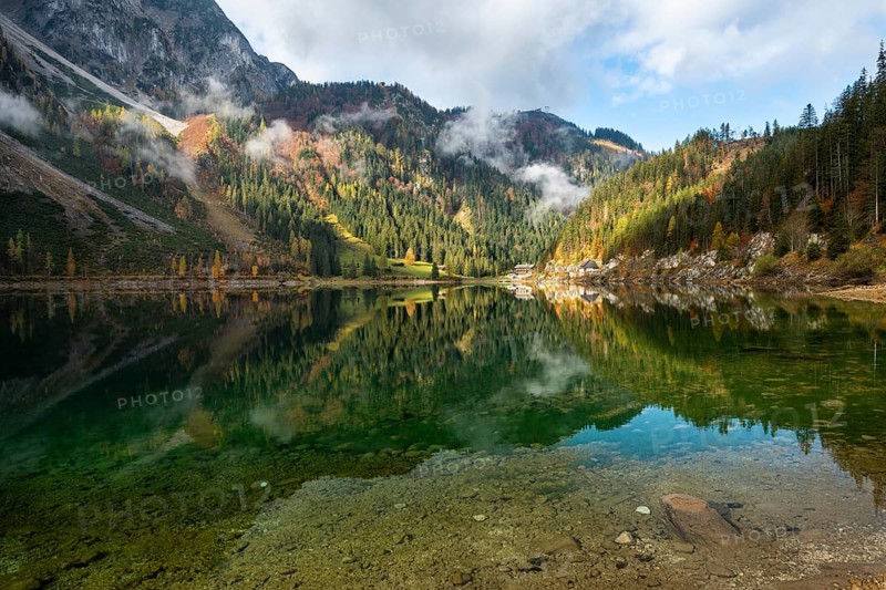 The Vordere Gosausee in autumn with a view of the Gasthof Gosausee. Sun and clouds. Reflection. Vorderer Gosausee, Gosau, Gosau Valley, Salzkammergut, Upper Austria, Austria, Europe