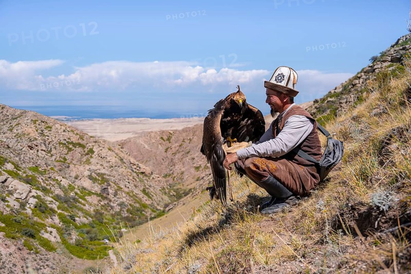 Traditional Kyrgyz eagle hunter with eagle in the mountains, near Kysyl-Suu, Kyrgyzstan, Asia