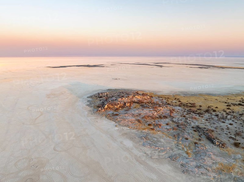 Rocky island with baobab trees in a dry salt pan, at sunset, aerial view, Kubu Island, Botswana, Africa