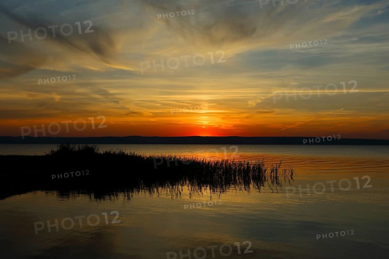Dramatic sunset at Lake Neusiedl in Austria with colourful orange and red illuminated cloudy sky, Podersdorf, Lake Neusiedl, Lake, Austria, Europe
