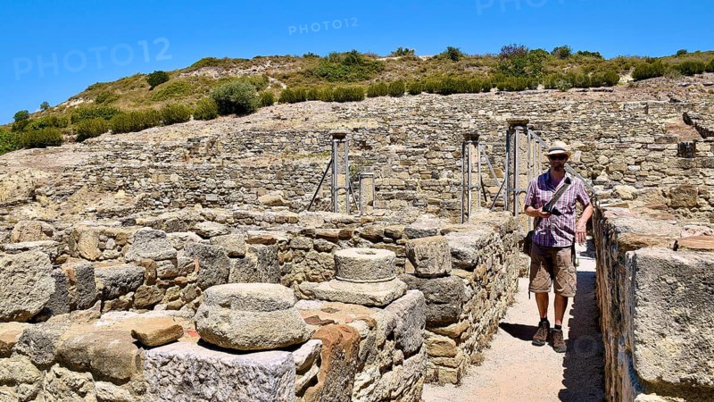 Man exploring an archaeological site with ancient stone ruins under a blue sky, Kamiros, Archaeological site, Ancient city, Foundation of Doric Greeks, Rhodes, Dodecanese, Greek Islands, Greece, Europe