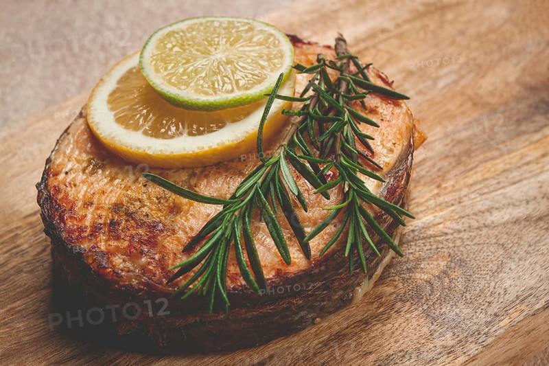 Salmon steak, fried, on a cutting board, top view, rosemary, lemon and lime, homemade, one serving, no people